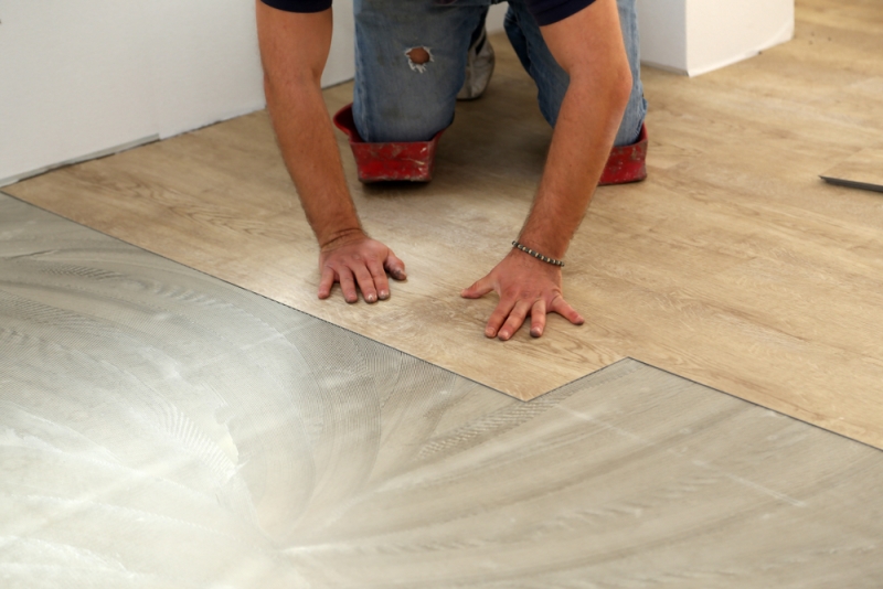 A worker laying vinyl plank flooring